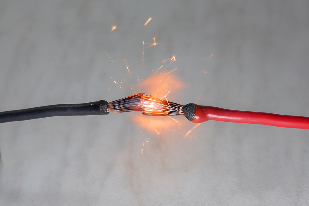Red and black wiring touching creating a flame.
