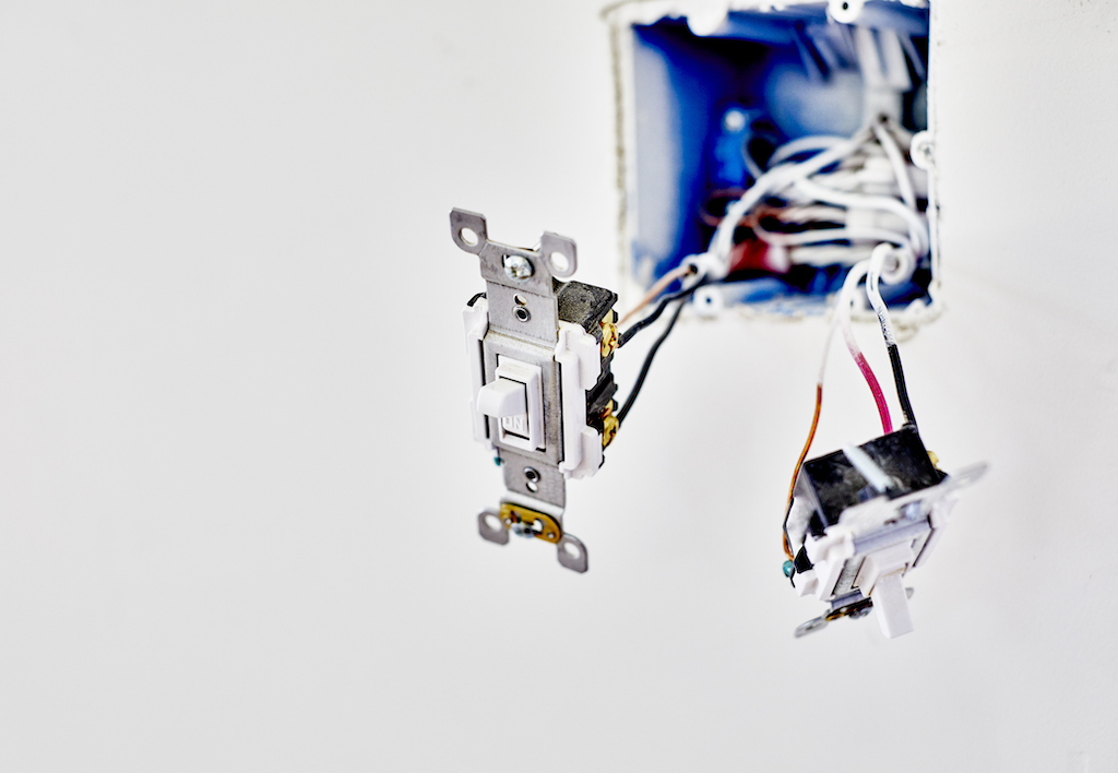 Inside light switch wiring on white wall.